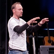 A man standing on stage with his hands outstretched.