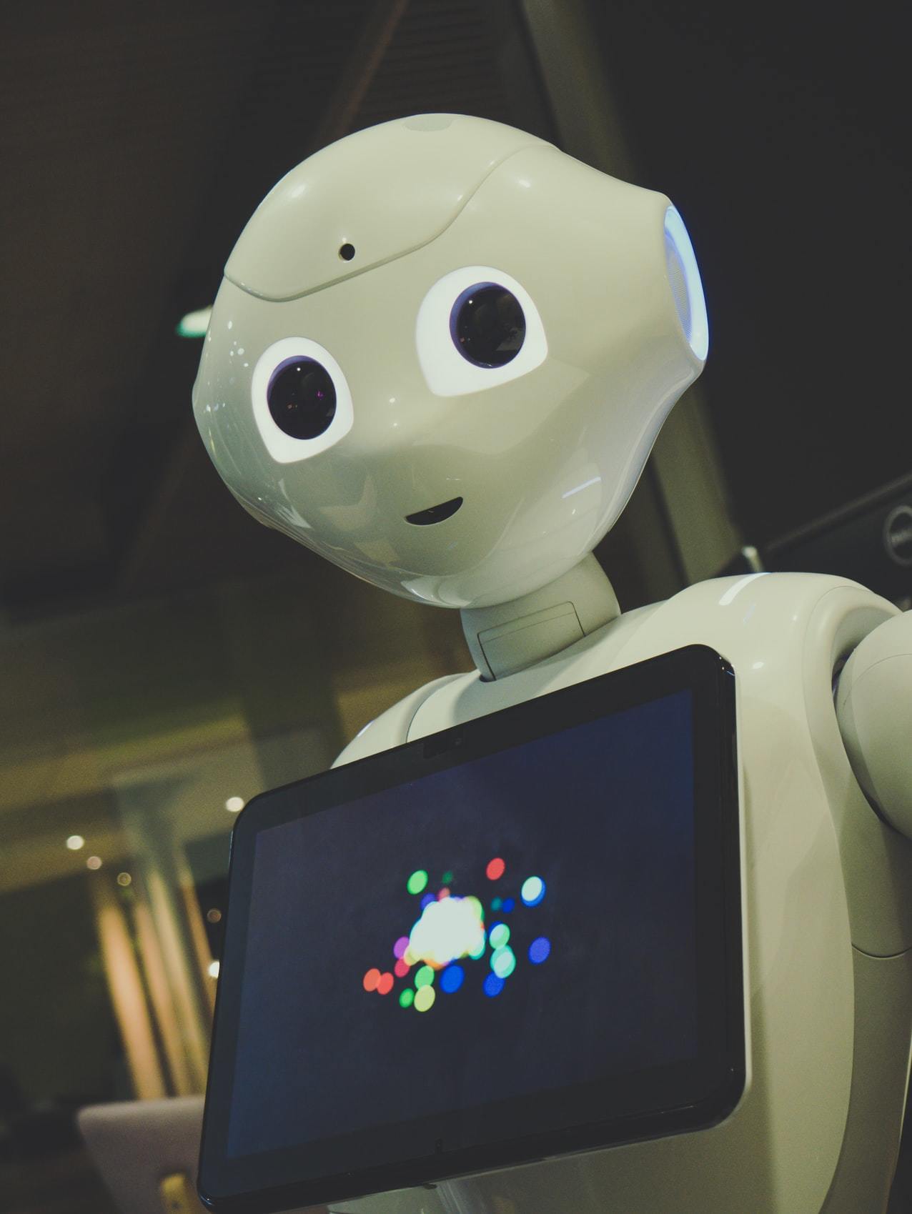 A white robot holding a tablet computer.